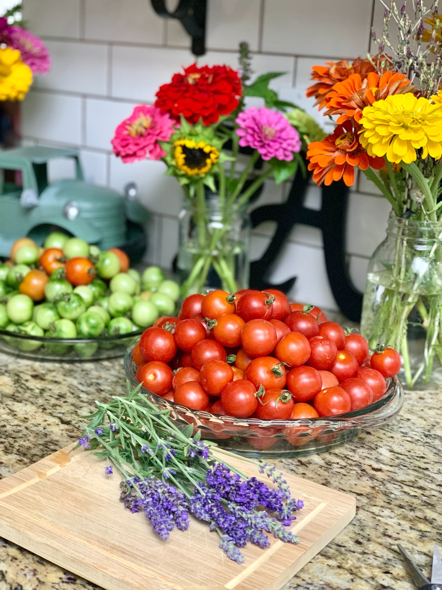 Red and green tomatoes, colorful garden flowers, and lavender on a kitchen counter